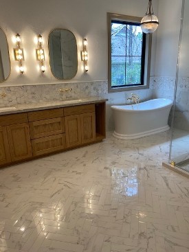 chevron style tile flooring with soaker tub and light wood bathroom vanity double sink with pendant lighting